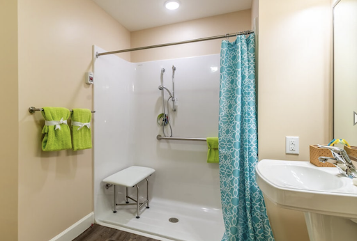 A modern and accessible shower space featuring a vibrant curtain and neatly organized towels.