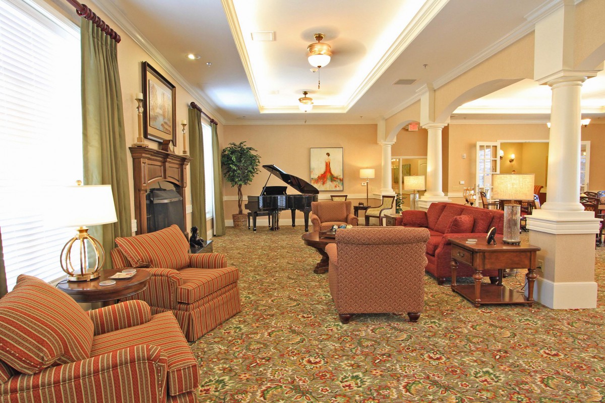 A spacious, elegantly decorated living room with comfortable seating and a grand piano.