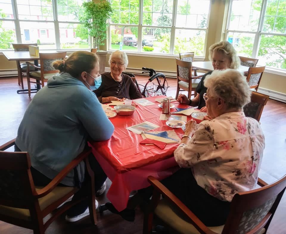 A group of seniors sitting around a table, engaging in conversation indoors.
