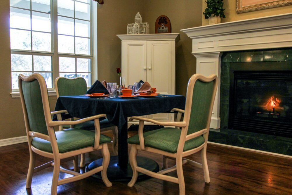 Cozy dining area with a table set near a fireplace, filled with natural light.