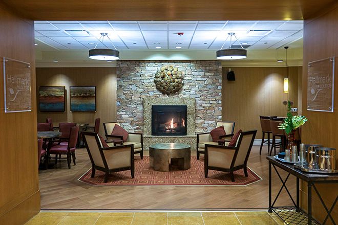 A cozy lounge with a fireplace, surrounded by comfortable chairs and a stone wall.