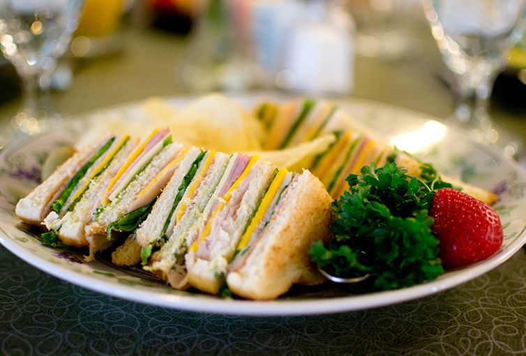 A plate of club sandwiches arranged in a circular pattern, garnished with fresh greens.