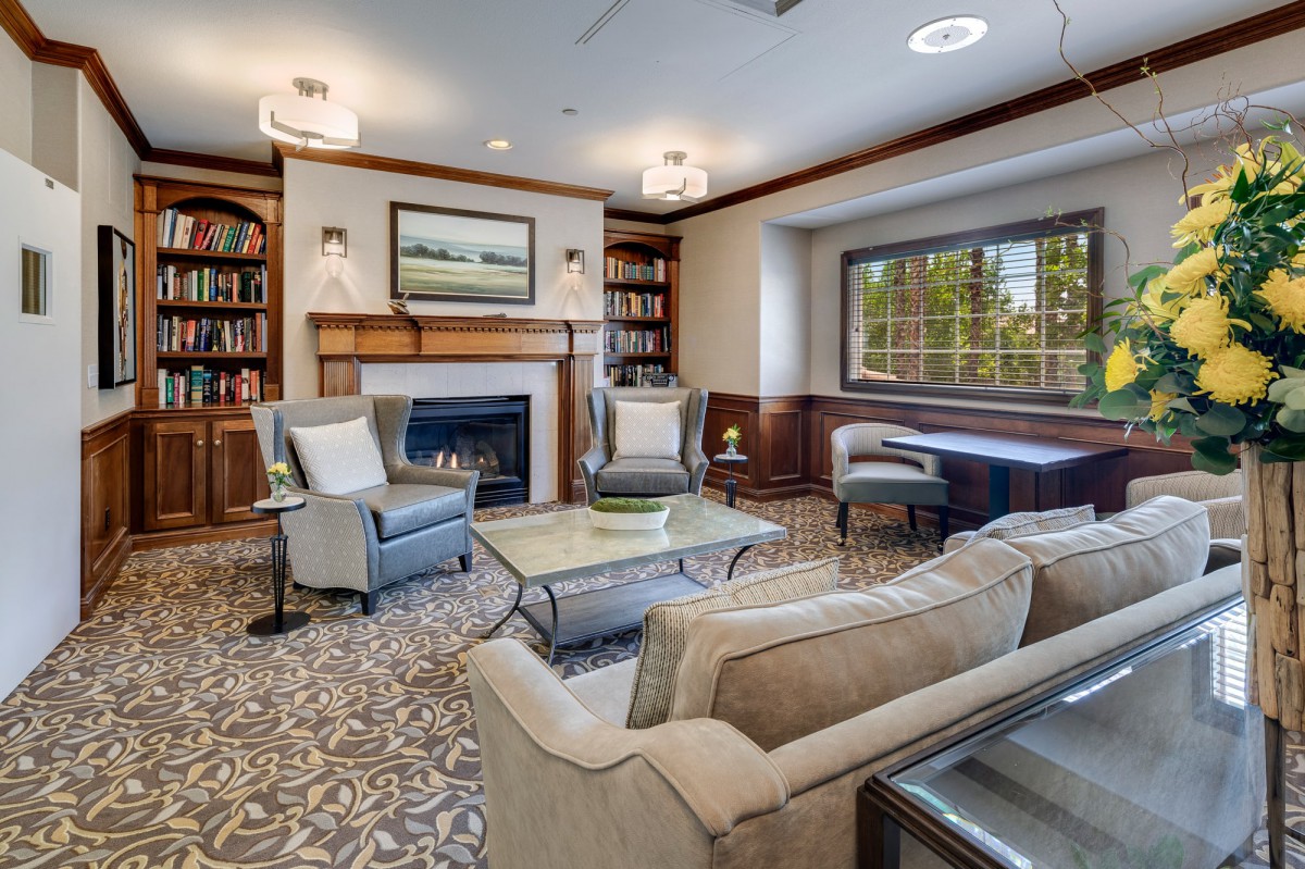 A cozy living room featuring a fireplace, elegant furniture, and built-in bookshelves.