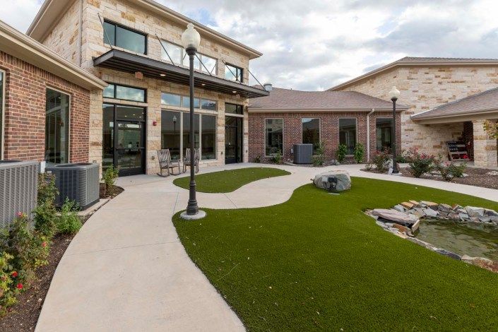 A modern residential complex featuring a landscaped patio area with artificial grass.
