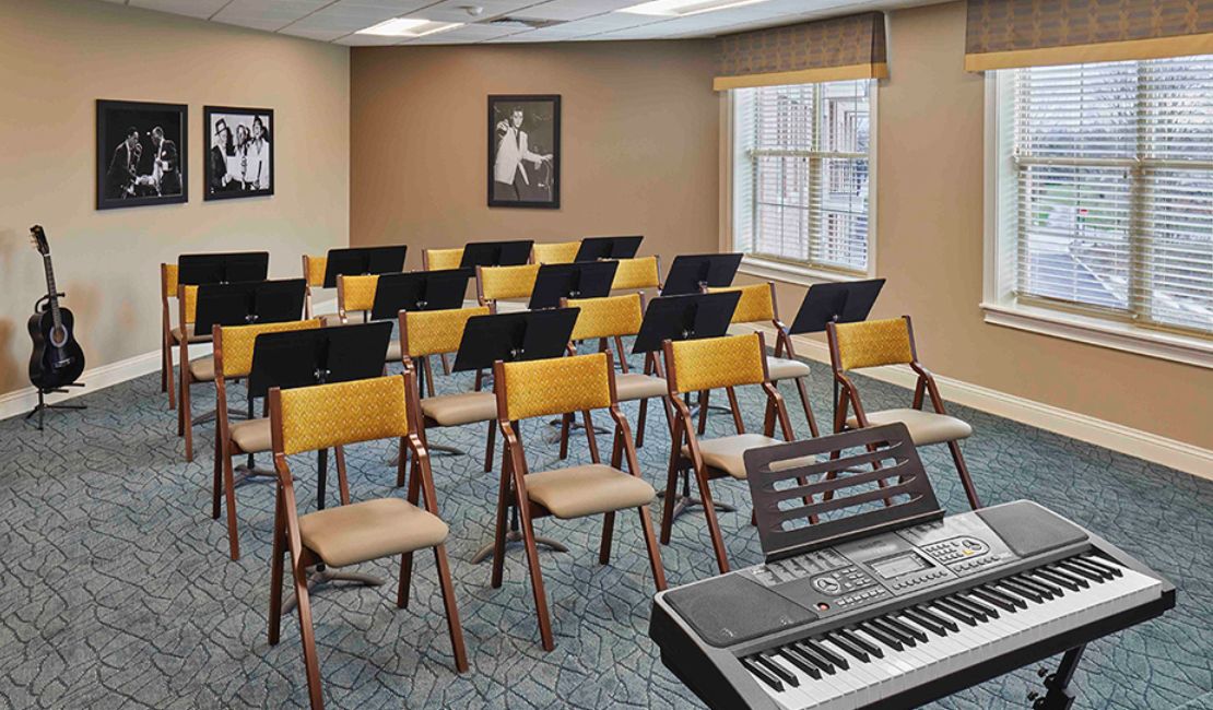 An empty music classroom with several chairs and music stands arranged in rows, featuring a keyboard at the front.