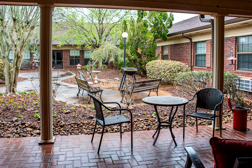 A serene courtyard featuring outdoor seating with benches and tables surrounded by lush greenery.