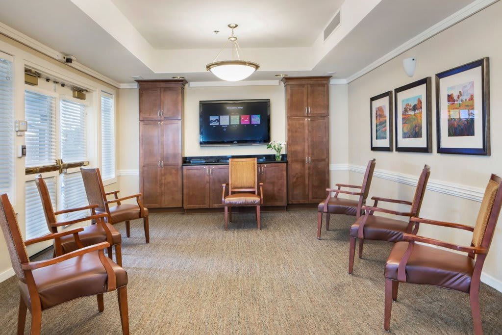 A modern waiting room featuring arranged chairs, a television, and decorative artwork on the walls.