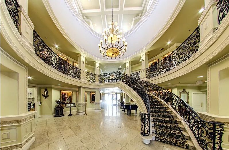 A luxurious lobby featuring a grand staircase and an ornate chandelier.