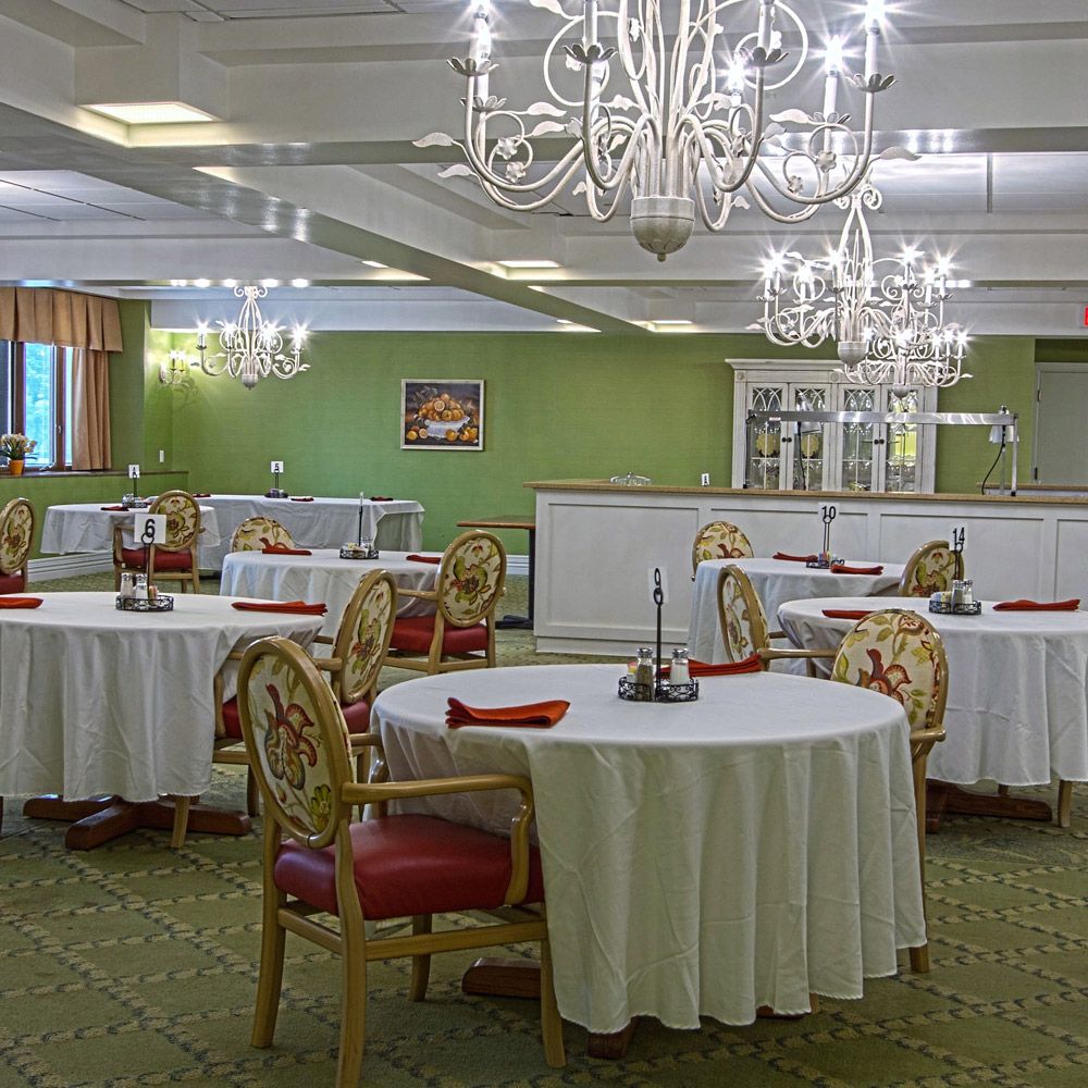 An elegant dining room with chandeliers and round tables set for a formal event.