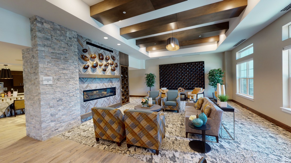A modern living room with elegant decor, featuring stylish seating, a stone fireplace, and artistic wall elements.
