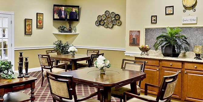 A well-decorated dining room with tables and chairs, featuring a television and floral arrangements.