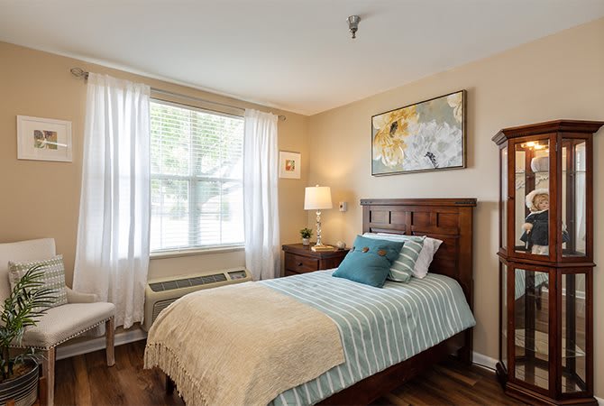 Cozy bedroom with a single bed, wooden floor, and bright natural light.