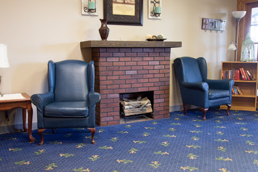 A cozy living room setting featuring blue armchairs, a brick fireplace, and decorative accents.