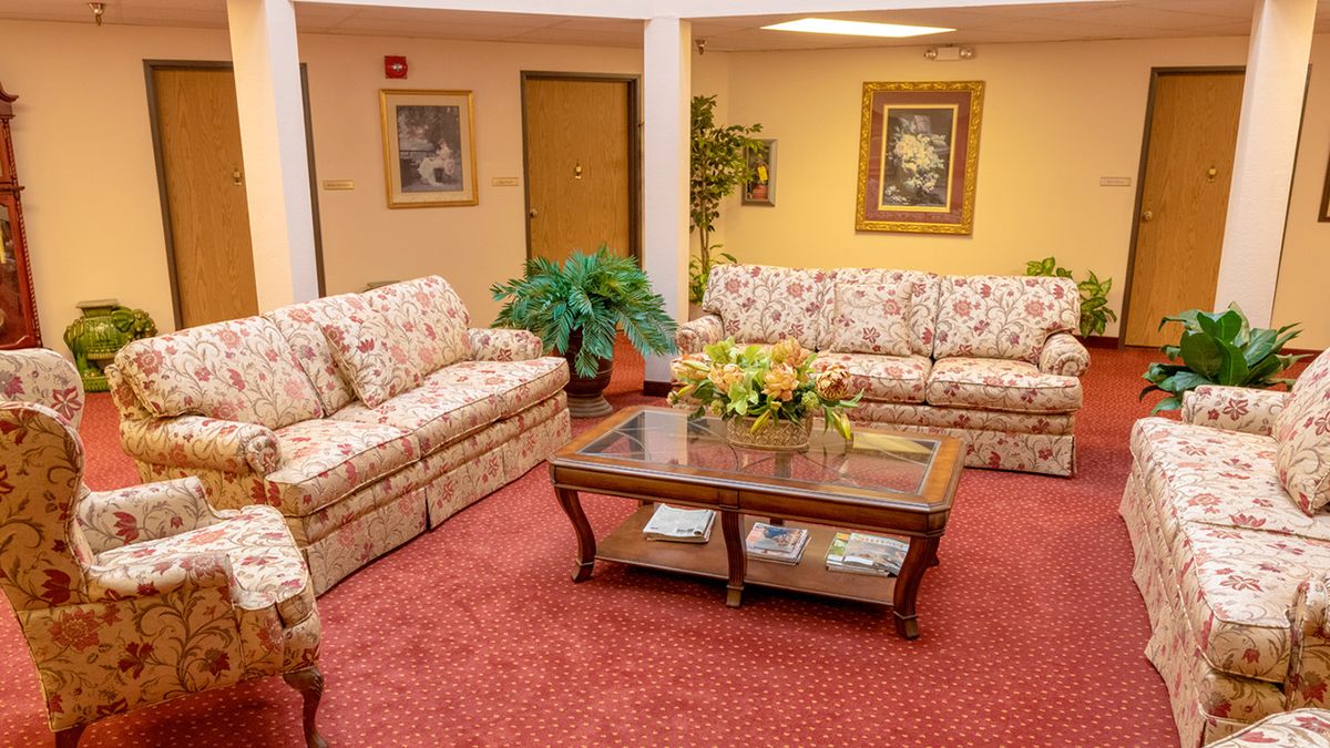 A cozy living room with floral sofas and a wooden coffee table adorned with flowers.