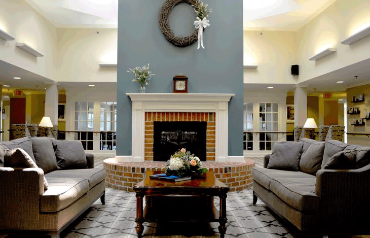 A cozy living room with a fireplace, adorned with a wreath and flanked by two sofas.