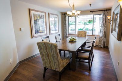 A well-lit dining room with a wooden table, several chairs, and decorative artwork on the walls.