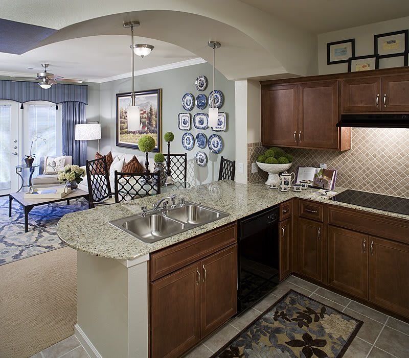Modern open-plan kitchen and living room with wood cabinets and granite countertops.