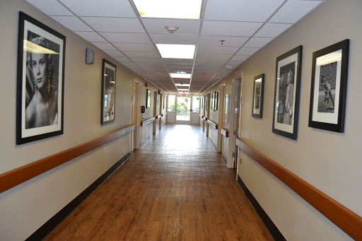 A well-lit hallway featuring wooden flooring and framed artwork on the walls.