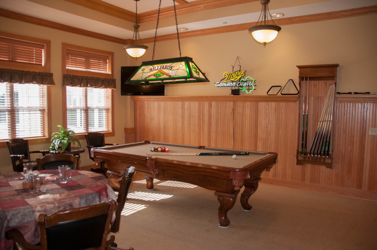 A cozy game room with a classic pool table and stylish wood paneling.