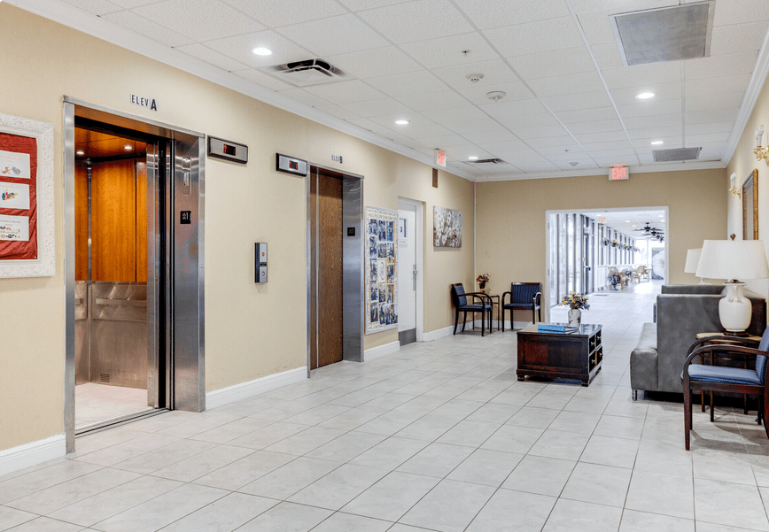 A modern lobby featuring elevator doors, a seating area, and a spacious hallway.