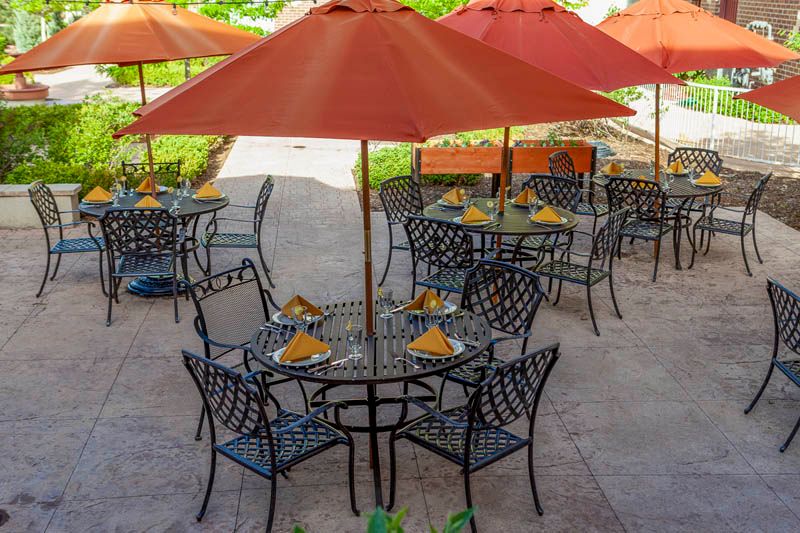 An outdoor dining area with tables and chairs under orange umbrellas.