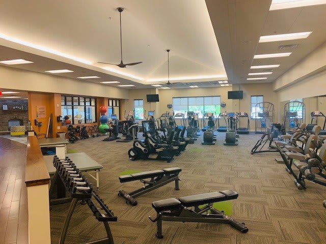 A spacious gym with various exercise equipment and workout benches.