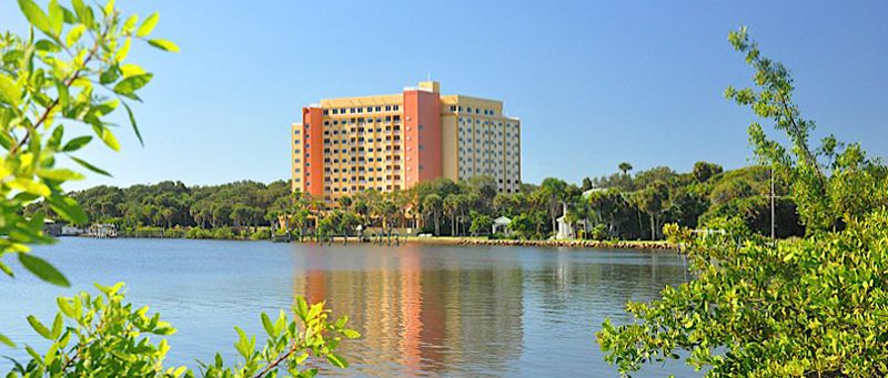 A hotel building with a scenic view of a lake and palm trees.