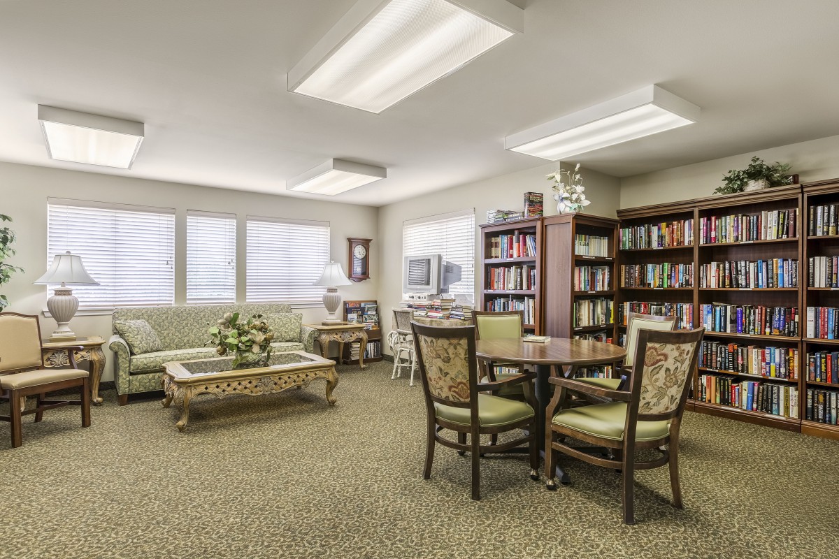 A cozy living area with sofas, a table with chairs, and bookshelves filled with books.