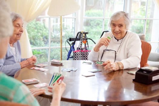 Elderly individuals enjoying a card game together indoors.