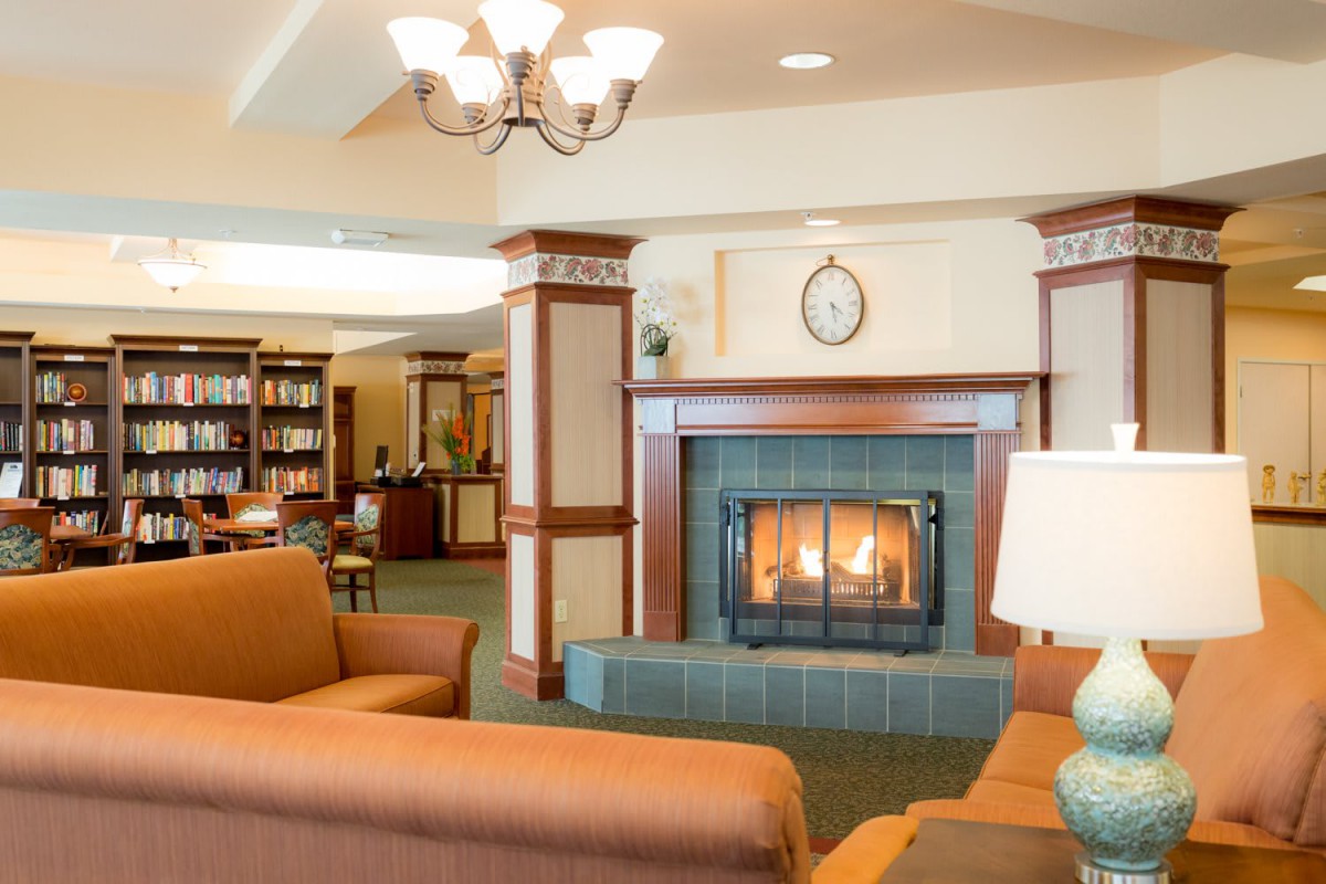 A cozy library lounge area with a fireplace and bookshelves.