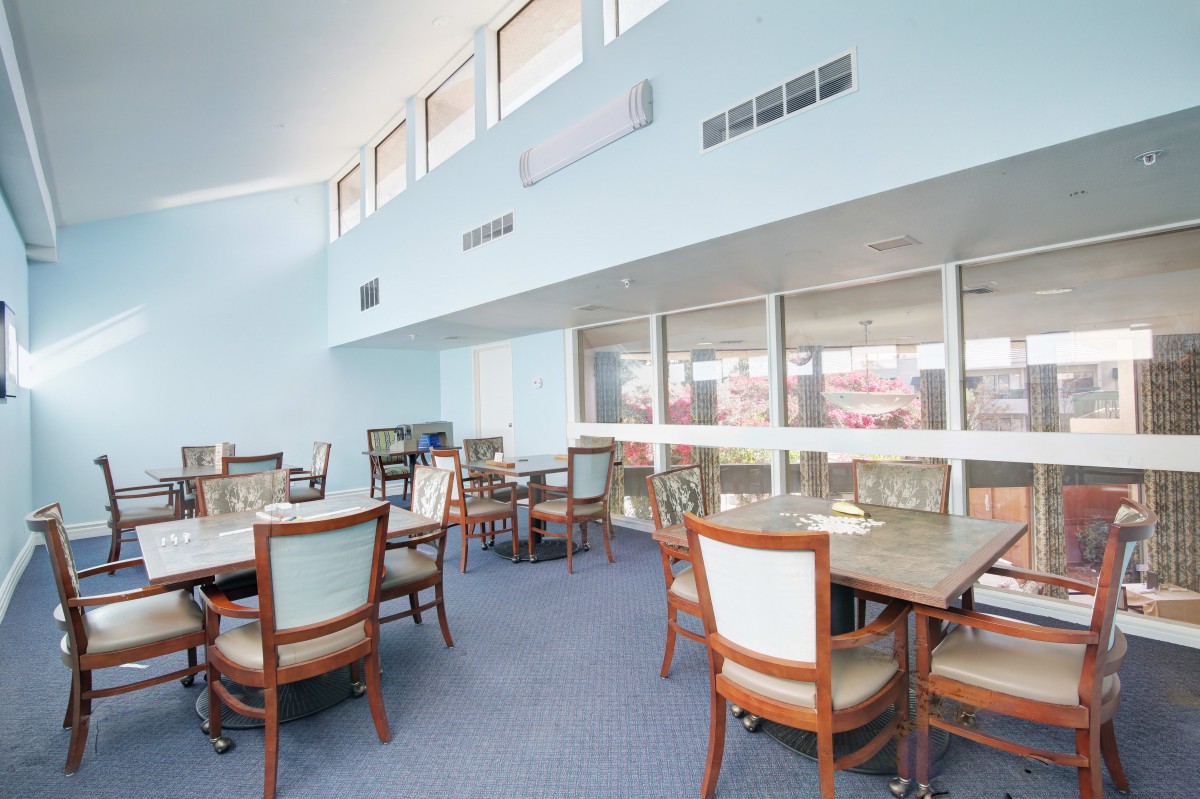 A spacious dining area with multiple tables and chairs, featuring a bright and airy interior design.