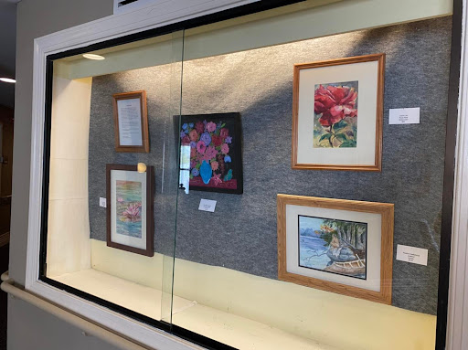 A display of various framed paintings showcased in an art gallery.