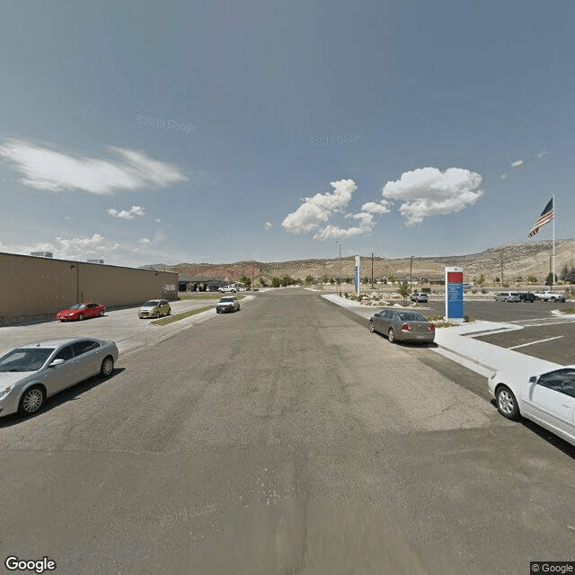 A daytime view of a parking lot with several cars parked under a partly cloudy sky.