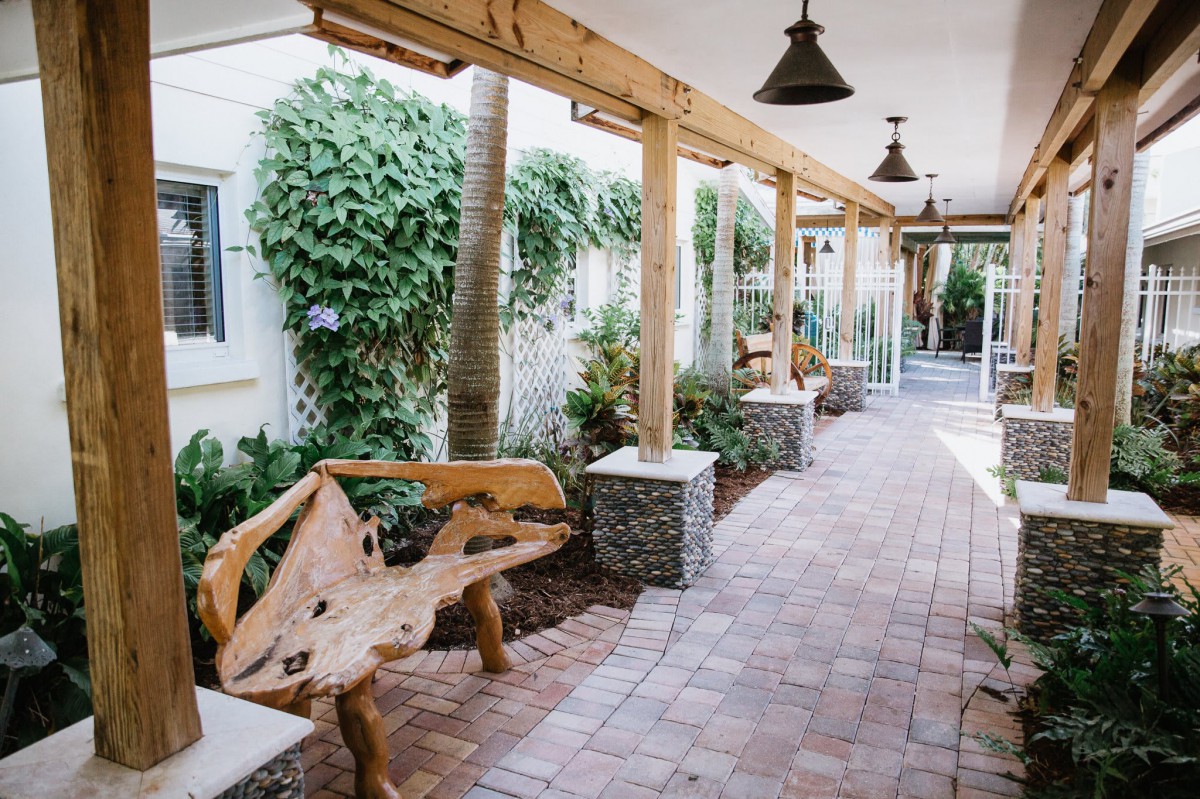 A serene outdoor walkway with wooden benches and lush greenery.
