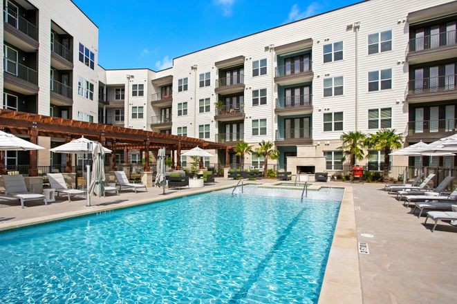 A luxurious apartment complex featuring a spacious outdoor swimming pool and modern design.