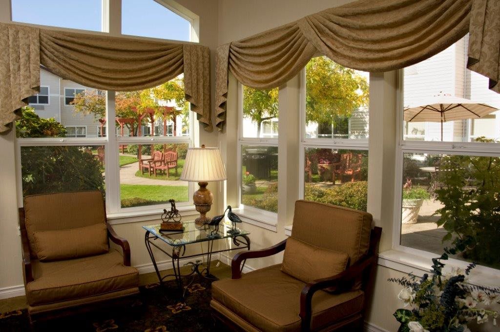 A cozy living room with armchairs and large windows overlooking a garden.