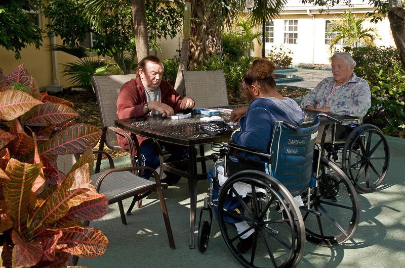 A group of people sitting around a table outdoors, with one person in a wheelchair.