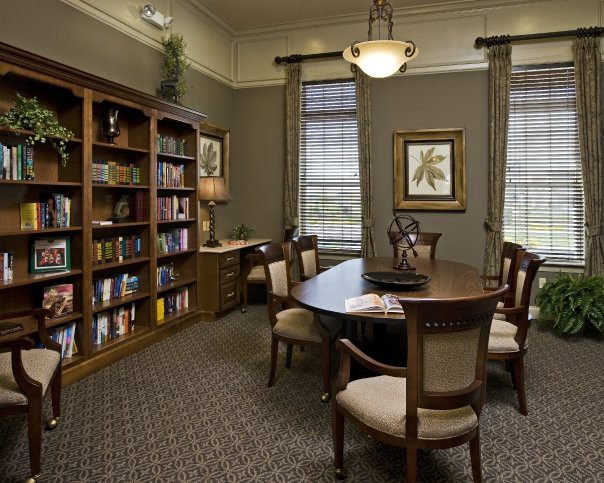 A well-lit library conference room with bookshelves, a central table, and several chairs.