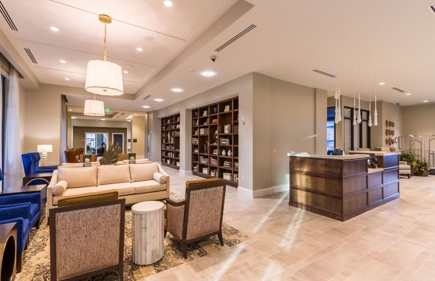 A modern lobby with comfortable seating, stylish lighting fixtures, and a wall-mounted bookshelf.
