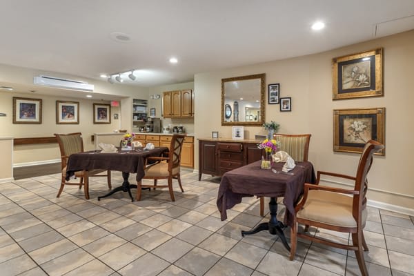 A cozy dining area with several tables and chairs, adorned with decorative mirrors and artwork on the walls.