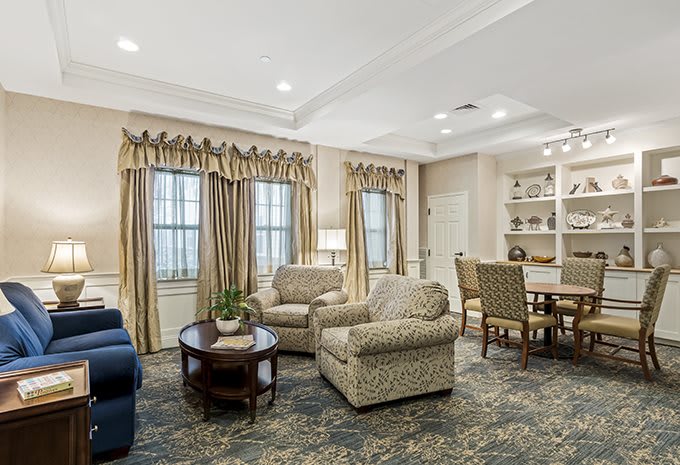A well-decorated living and dining area featuring comfortable armchairs, a sofa, and elegant curtains.