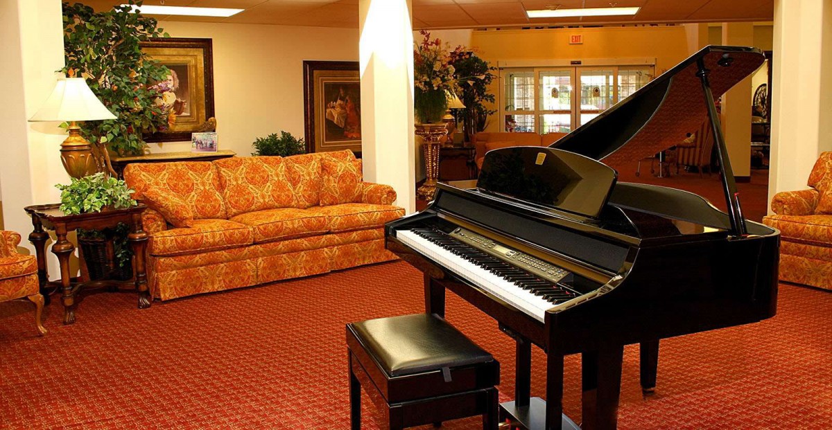 A cozy living room featuring a grand piano and an elegant sofa.