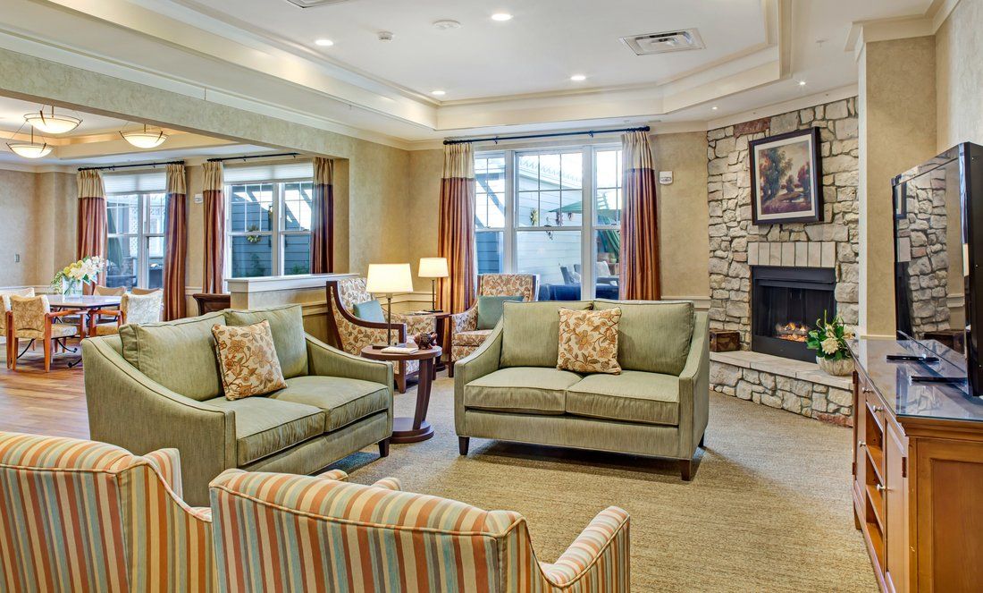 A cozy living room with sofas, a fireplace, and ample natural light from large windows.