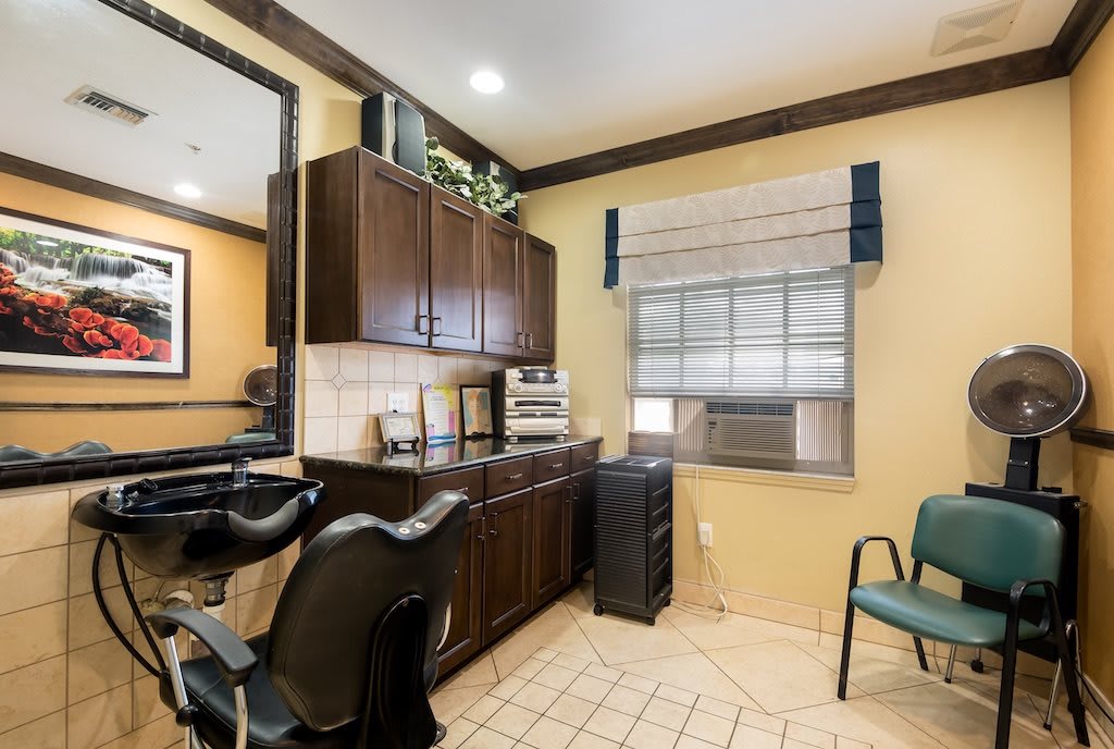 A modern hair salon interior with styling chairs, a large mirror, and a cabinet for supplies.