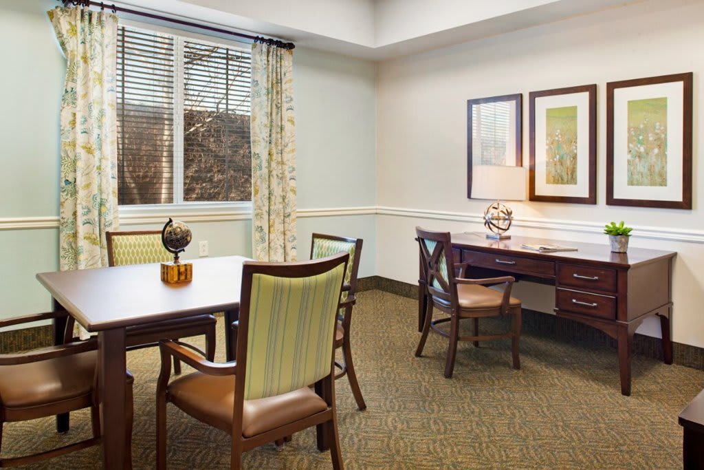 A well-lit office space featuring a desk, chairs, and decorative items.