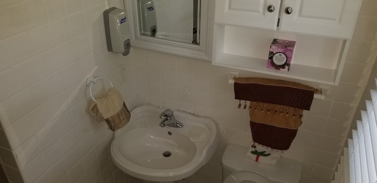 A compact bathroom with a sink, mirror, and towel.