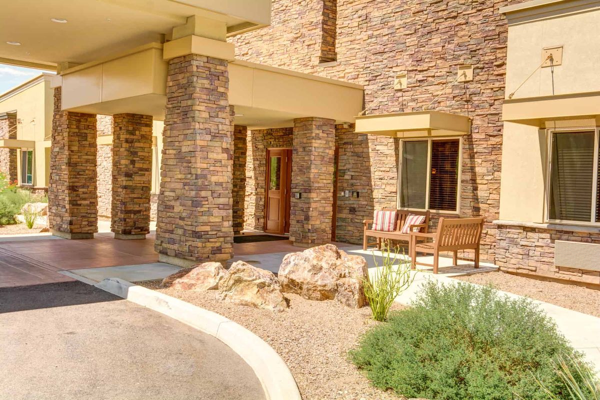 The entrance of a building with a stone facade and desert landscaping.