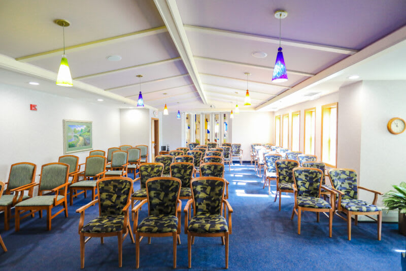 A brightly lit conference room with rows of patterned chairs and large windows.