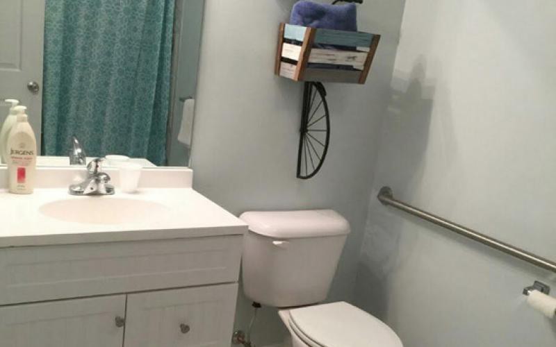 A clean, minimalist bathroom with a toilet, sink, and wall-mounted storage shelves.