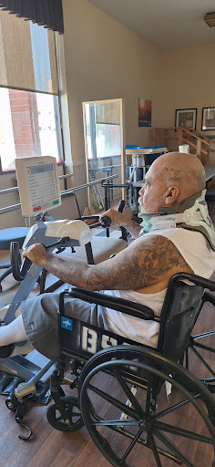 A patient engaged in a rehabilitation exercise using adaptive equipment.